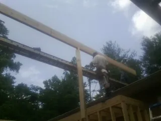 Carpenter setting a ridge beam over a new addition frame — Ice Dam Removal by Roofing Brothers in Blue Jay