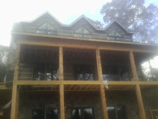 Dormers and porch framing on a large log home under construction — Roof Coating work by our crew in Blue Jay