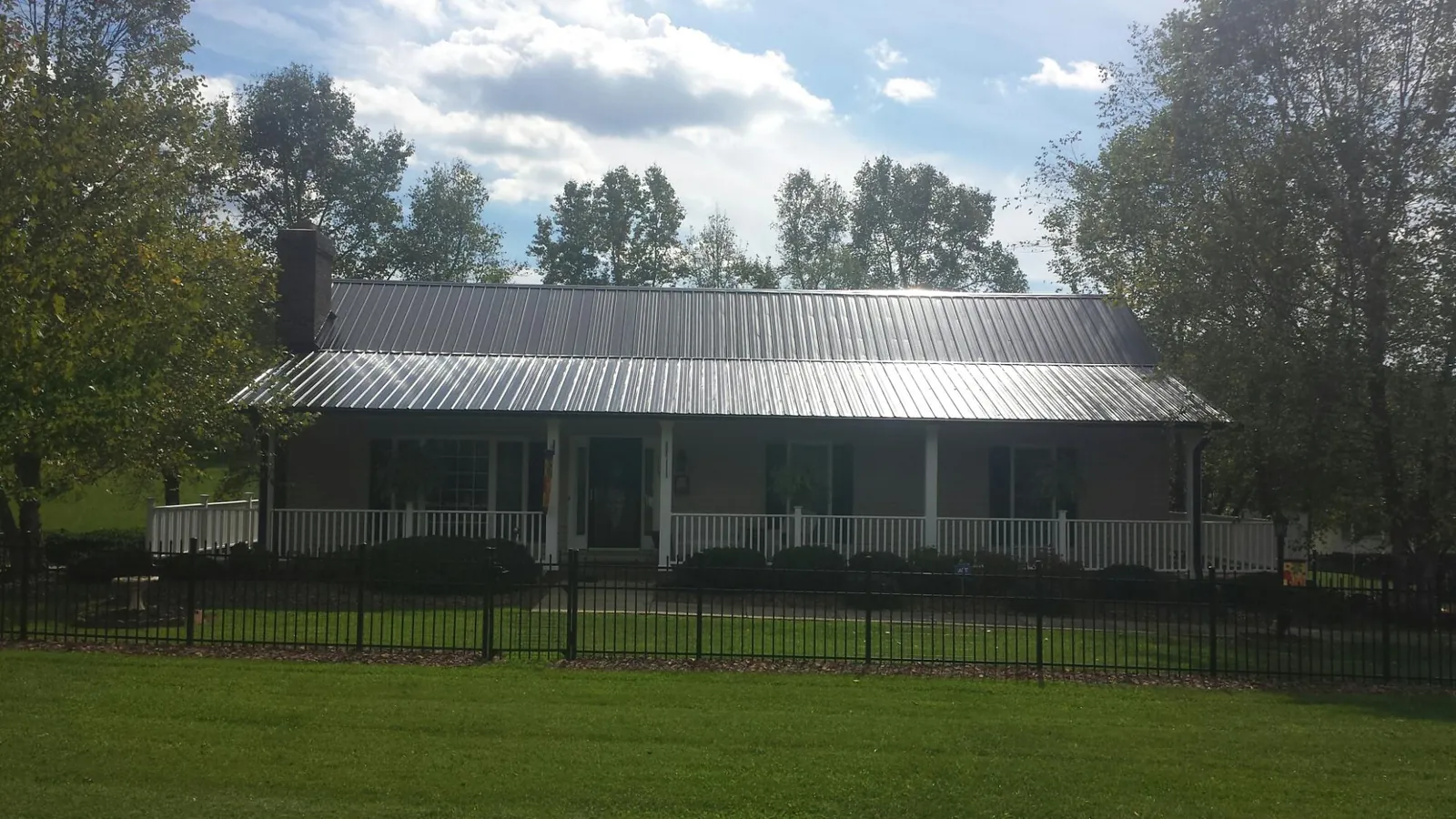 Gray metal roof on a brick ranch with a full width front porch — Gutter Guard Installation work by our crew in Blue Jay
