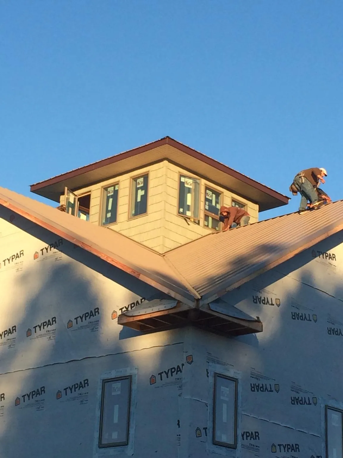 Roofers working around a rooftop cupola on a new metal roof at sunset — Roof Waterproofing in Blue Jay by Roofing Brothers